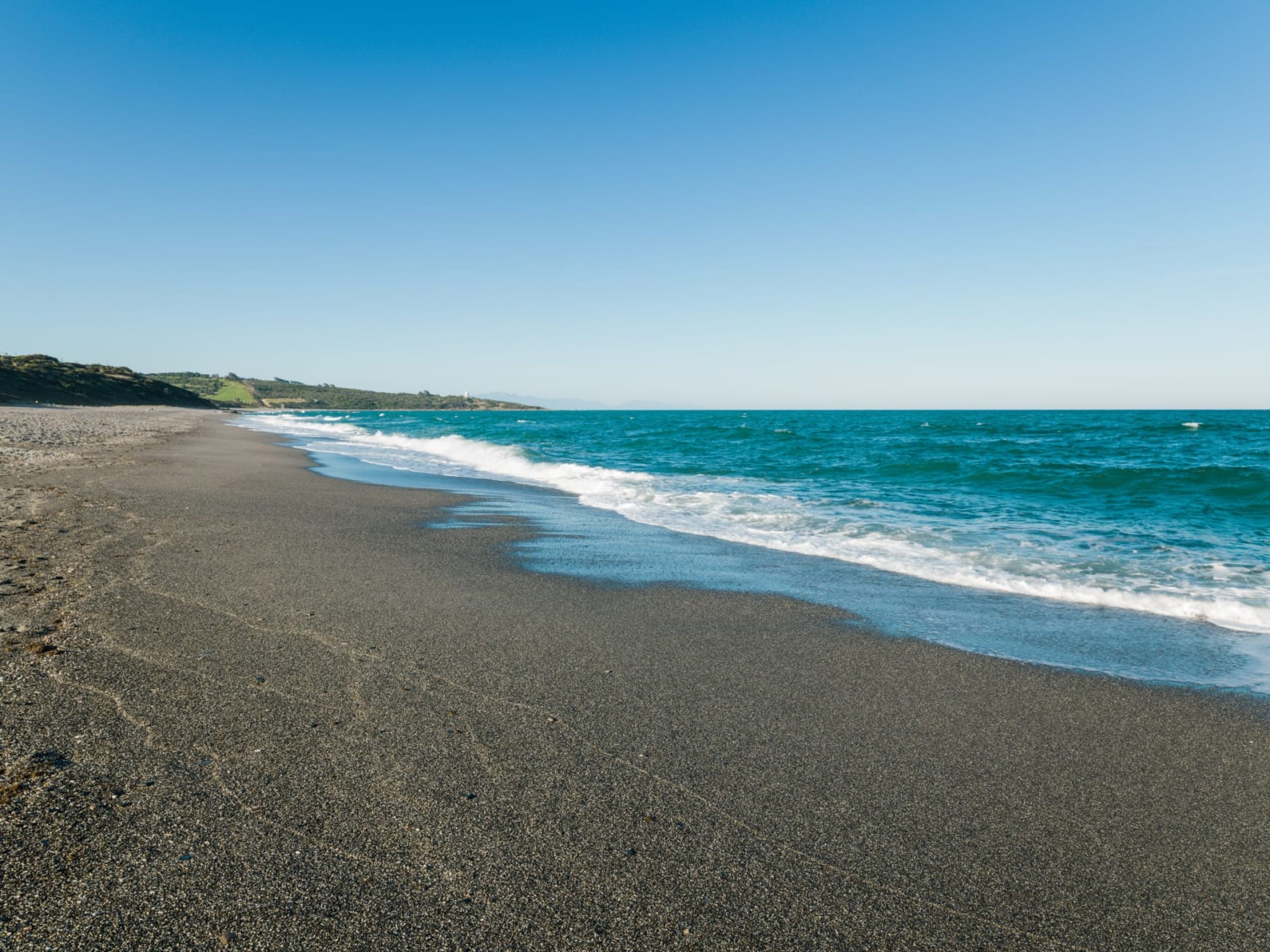 Playa tranquila en San Roque con arena oscura y mar azul